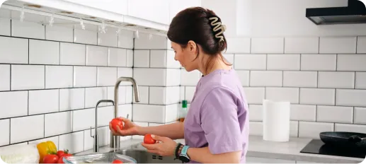 Mujer lavando verduras con agua de la llave en una cocina